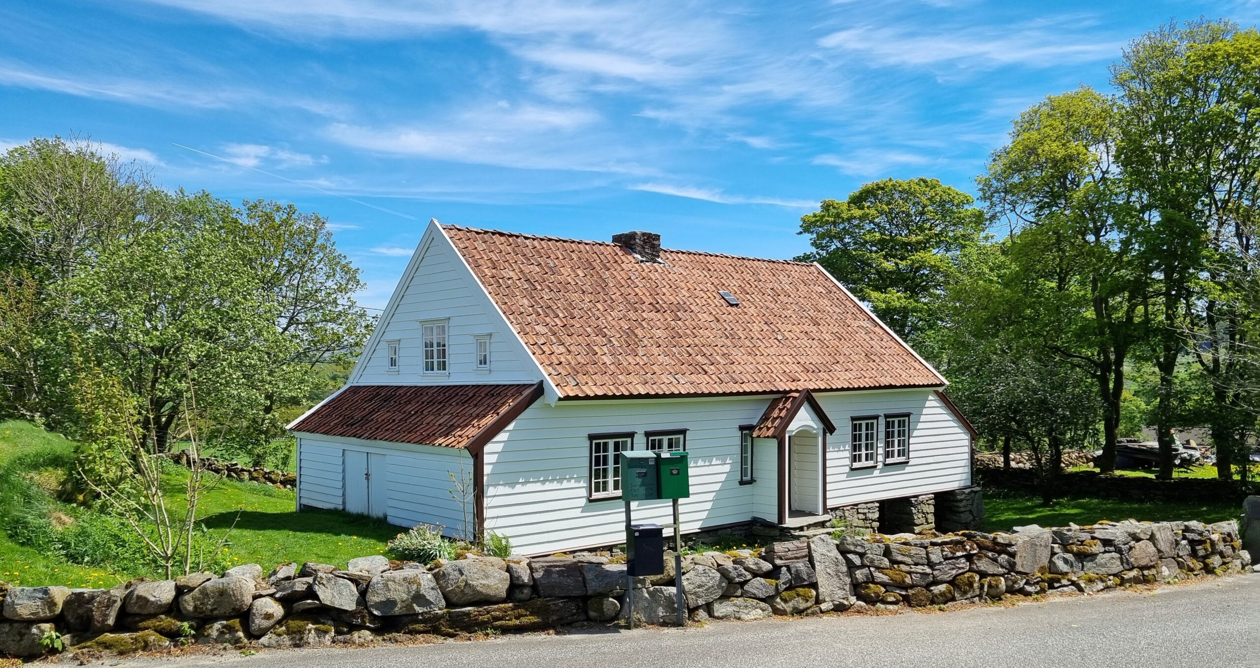 Garborgheimen, eit kvitt jærhus med teglstak, bak ein steingard