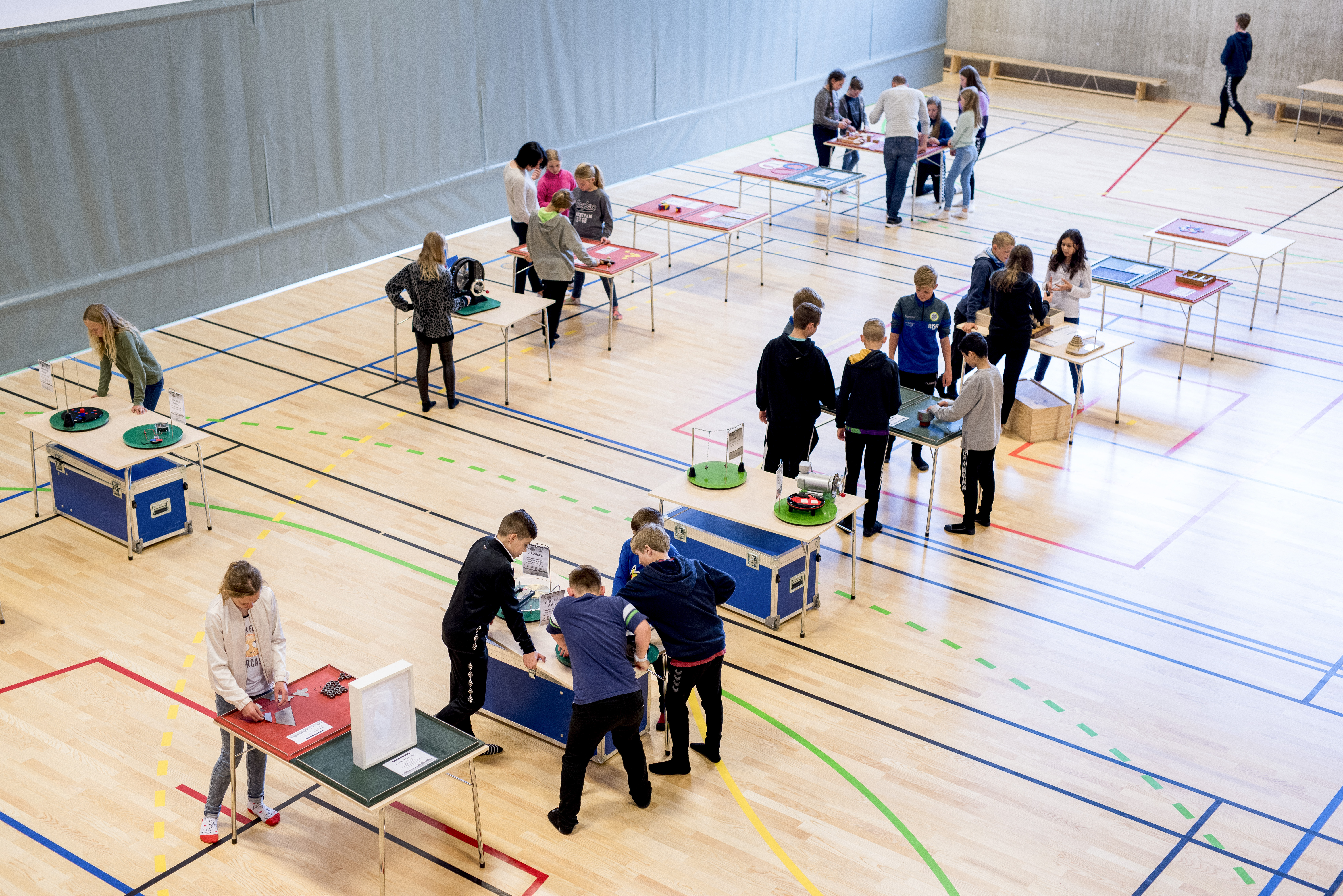 Elevar prøver eksperimenta i den mobile utstillinga til Science Circus i ein gymsal