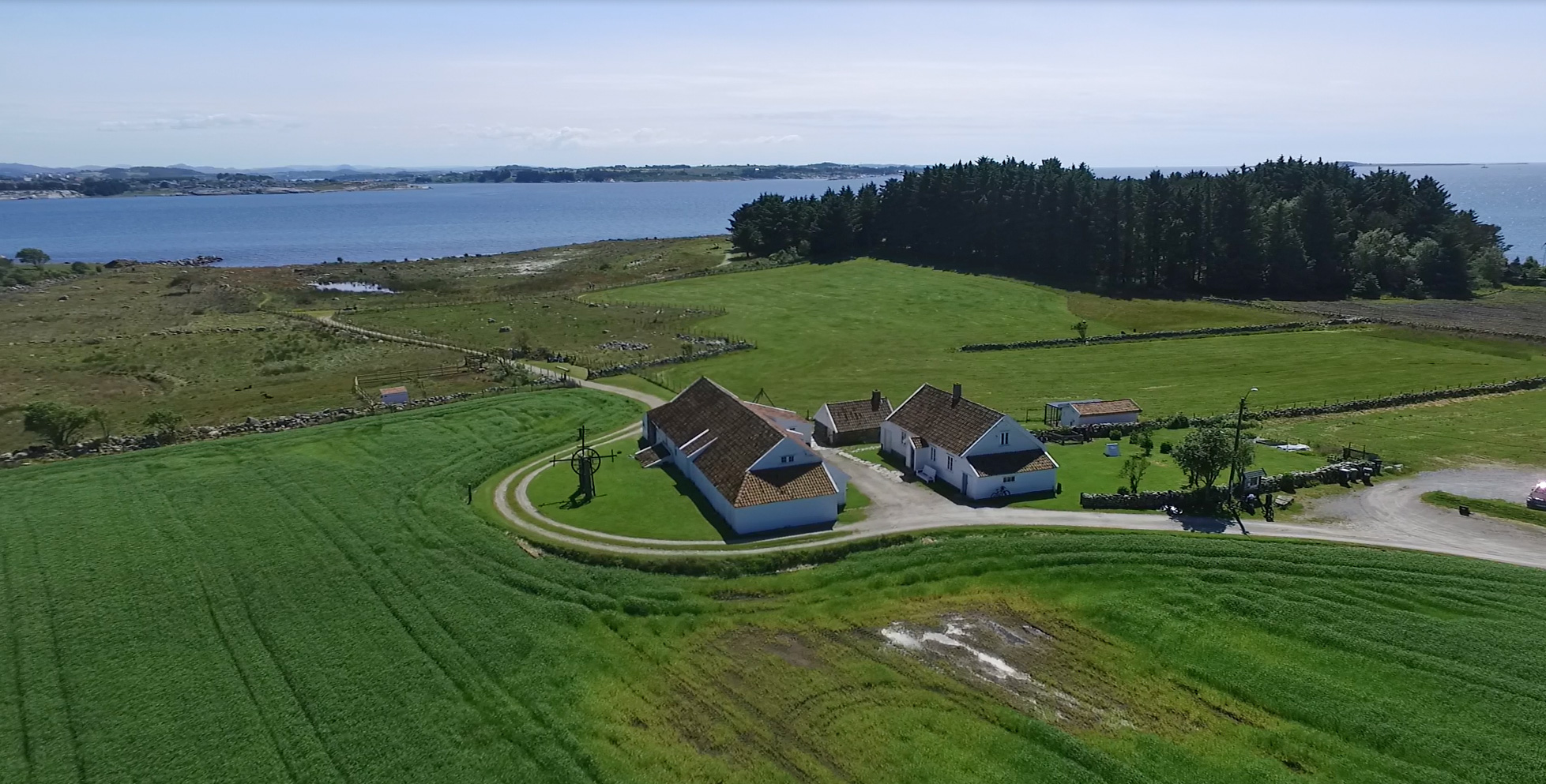 Vistnestunet sett frå lufta, med grøne jorde og sjøen bak